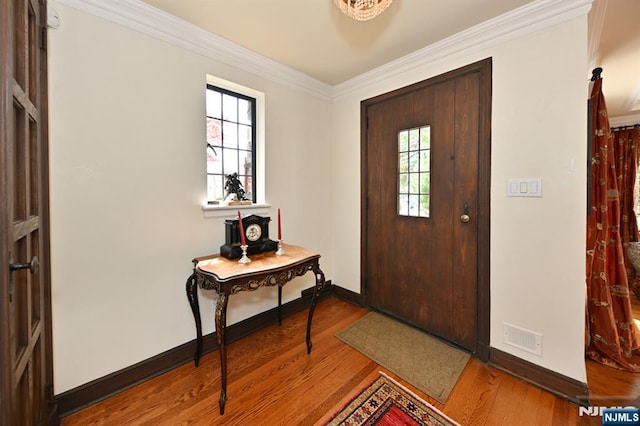 entrance foyer with baseboards, crown molding, wood finished floors, and a healthy amount of sunlight