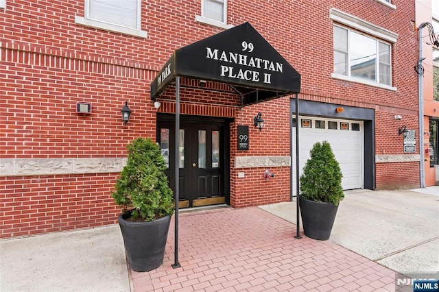 99 Park Ave Unit 5D, Hoboken, NJ 07030 - view of exterior entry with brick siding, a garage, and concrete driveway