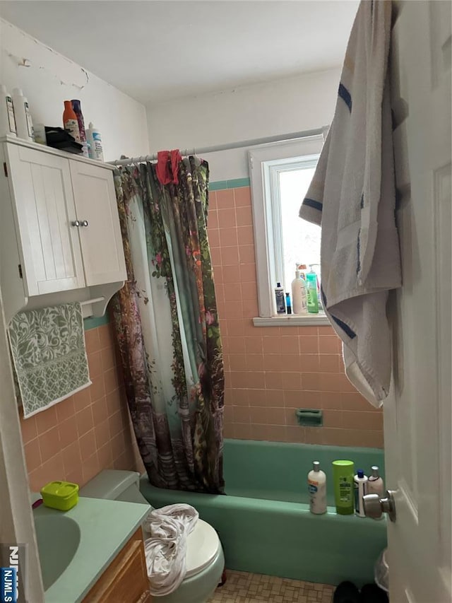 full bath with vanity, tile walls, and shower / tub combo