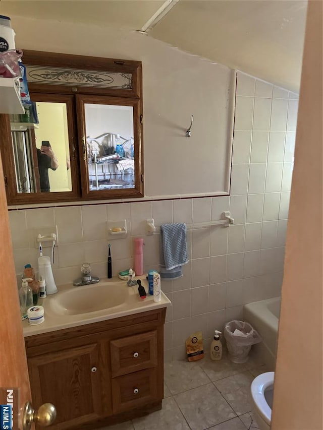 full bath with vanity, tile walls, a tub, and tile patterned flooring