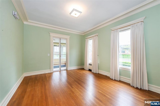 spare room with crown molding, wood finished floors, and baseboards