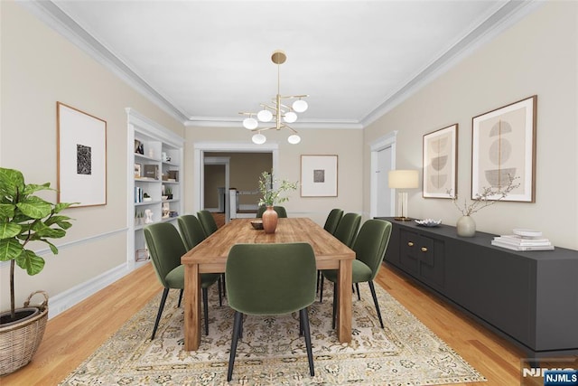 dining area featuring a notable chandelier, crown molding, built in features, and light wood-style floors