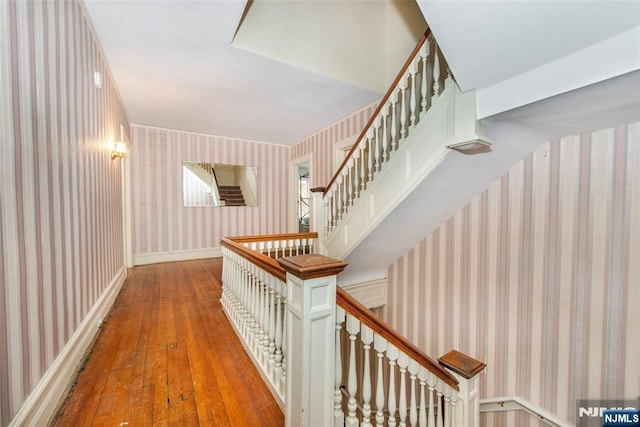 interior space featuring an upstairs landing, wood-type flooring, and wallpapered walls