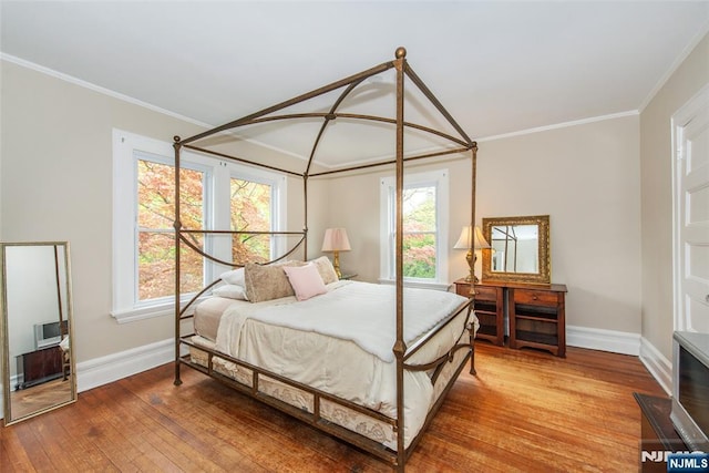 bedroom with baseboards, multiple windows, hardwood / wood-style floors, and crown molding
