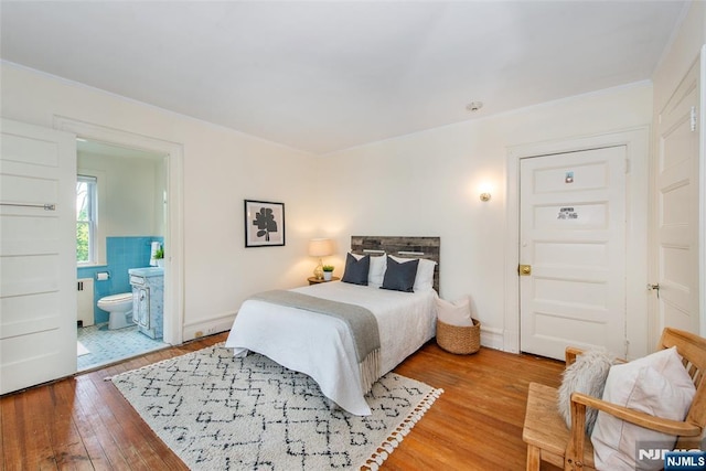 bedroom featuring radiator, ensuite bathroom, light wood finished floors, and ornamental molding