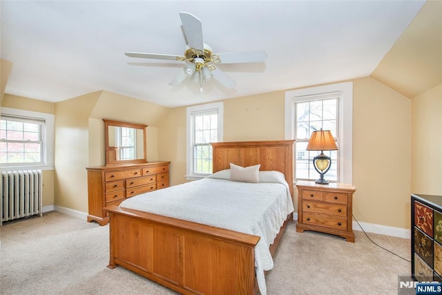 bedroom with light carpet, baseboards, multiple windows, and radiator heating unit