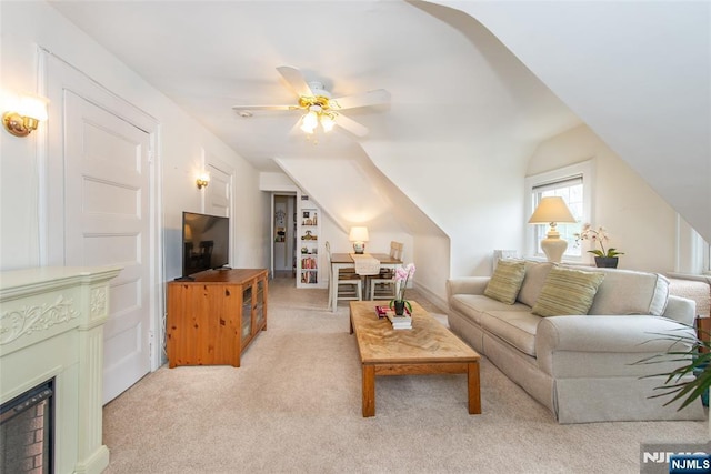 living area featuring light carpet, a fireplace, lofted ceiling, and ceiling fan