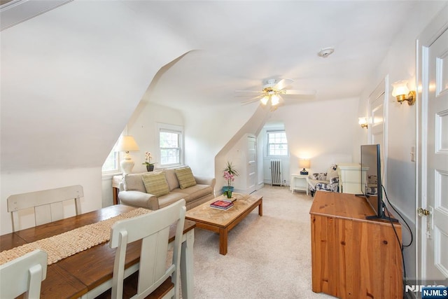 living room featuring radiator, vaulted ceiling, ceiling fan, and light carpet