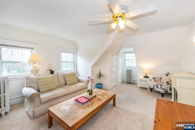 living area featuring lofted ceiling, radiator, light colored carpet, and plenty of natural light