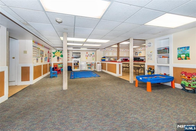 recreation room featuring carpet, a drop ceiling, and built in shelves