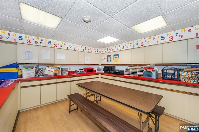 interior space with a paneled ceiling and light wood-style floors