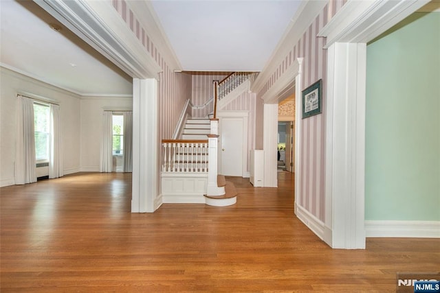 interior space featuring wallpapered walls, stairway, wood finished floors, and crown molding