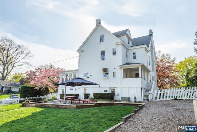 back of property featuring a chimney, a lawn, fence, central AC, and stucco siding