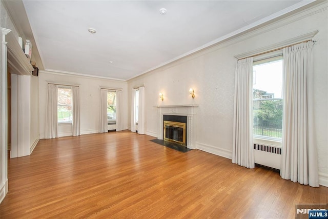 unfurnished living room featuring light wood finished floors, crown molding, baseboards, and a high end fireplace
