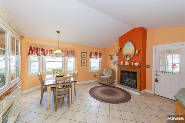 dining space featuring baseboards, a glass covered fireplace, lofted ceiling, and light tile patterned flooring
