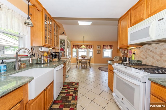 kitchen featuring a sink, light tile patterned floors, decorative backsplash, and white appliances