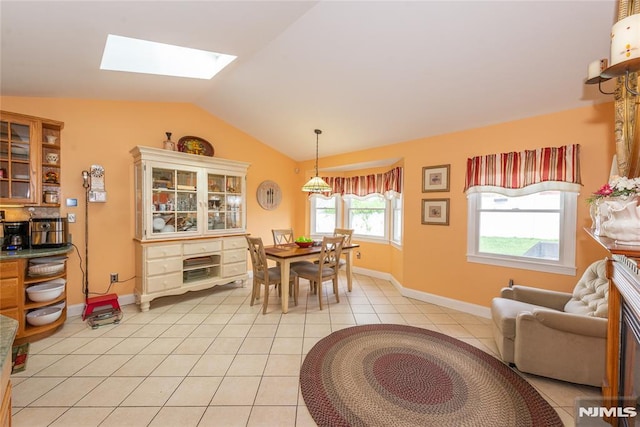 dining room with light tile patterned floors, baseboards, and vaulted ceiling with skylight
