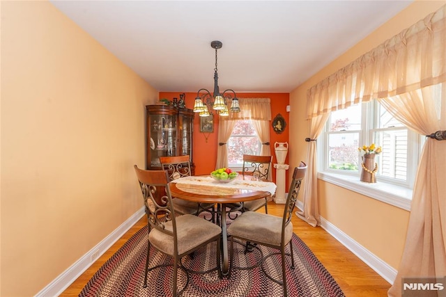 dining room featuring baseboards, light wood finished floors, and a notable chandelier