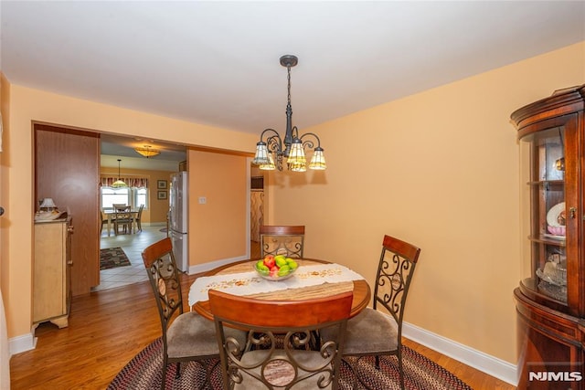 dining area with baseboards, a chandelier, and wood finished floors