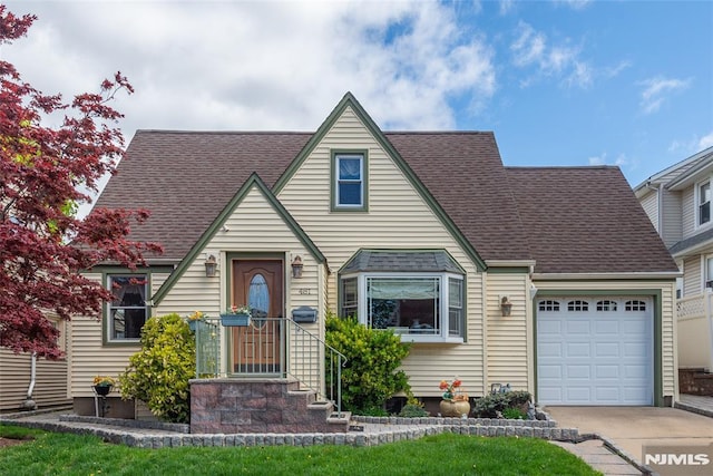 view of front of property with an attached garage, a shingled roof, and driveway