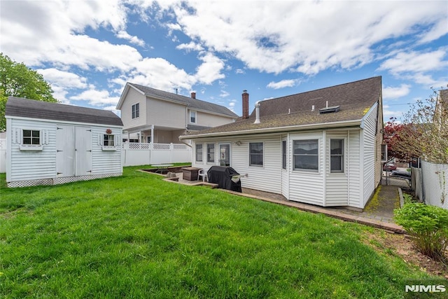 back of property with a lawn, a fenced backyard, a storage shed, and an outdoor structure
