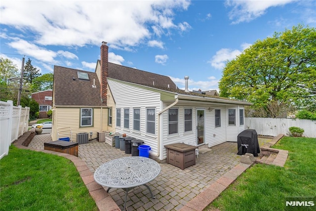 rear view of house featuring a fenced backyard, a patio area, an outdoor fire pit, central air condition unit, and a yard