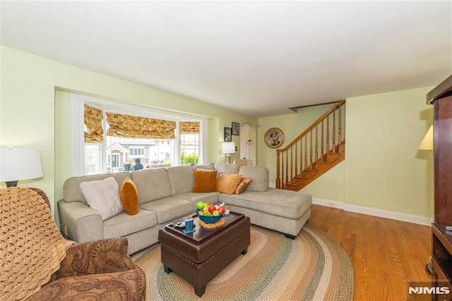 living area with stairs, baseboards, and wood finished floors