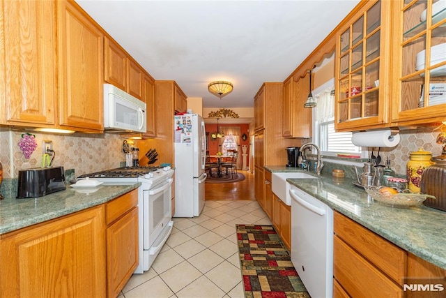 kitchen featuring white appliances, light tile patterned floors, a sink, and tasteful backsplash