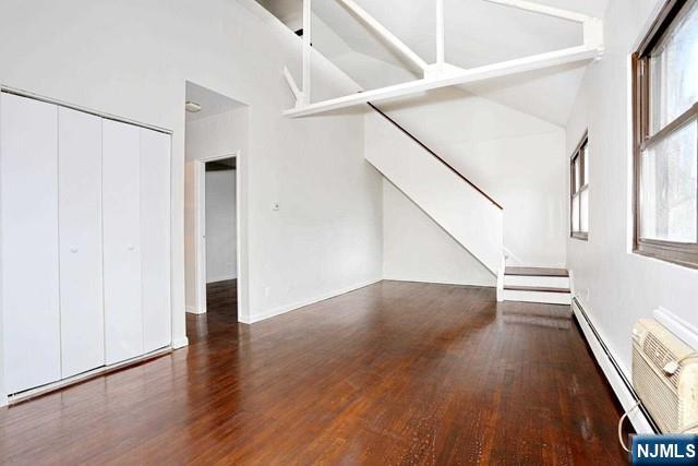 57 Brookway Ave Unit 2C, Englewood, NJ 07631 - unfurnished living room with wood finished floors, plenty of natural light, lofted ceiling, and stairway