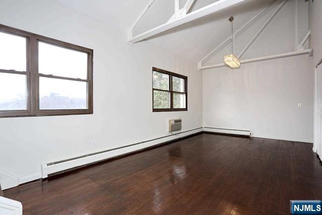 57 Brookway Ave Unit 2C, Englewood, NJ 07631 - empty room featuring vaulted ceiling with beams, a baseboard radiator, and wood finished floors