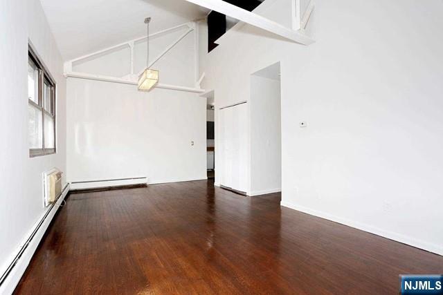 57 Brookway Ave Unit 2C, Englewood, NJ 07631 - unfurnished dining area with wood finished floors, baseboards, baseboard heating, high vaulted ceiling, and a baseboard radiator