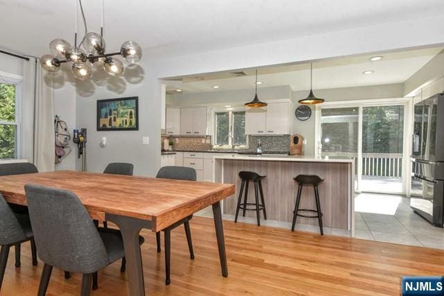 dining area featuring recessed lighting, a notable chandelier, and light wood finished floors
