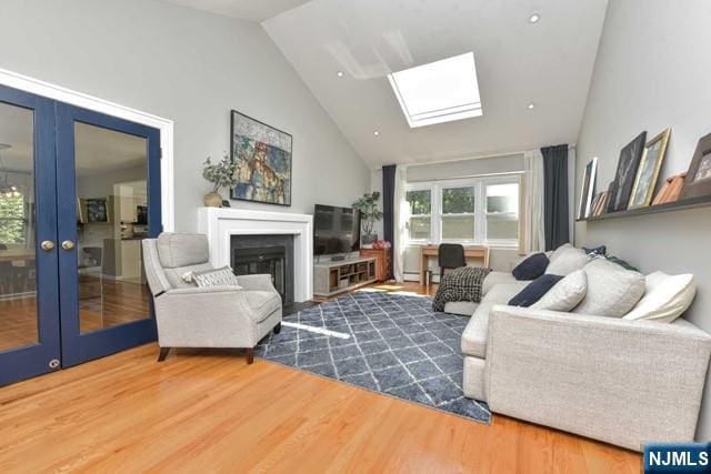 living area featuring a fireplace, a skylight, french doors, and wood finished floors