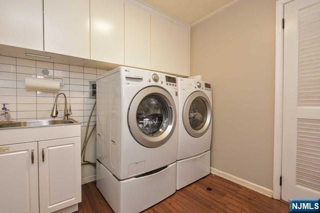 clothes washing area with baseboards, dark wood-style floors, washing machine and clothes dryer, a sink, and cabinet space