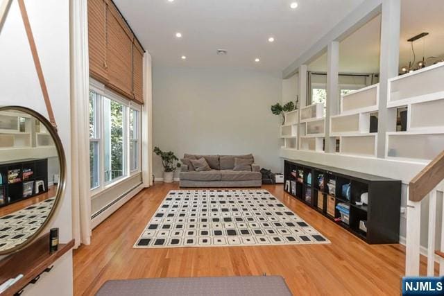 living area with wood finished floors, recessed lighting, and a baseboard heating unit