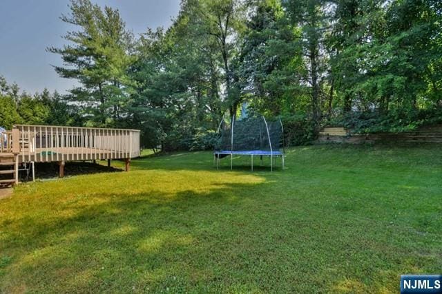 view of yard featuring a trampoline and a deck