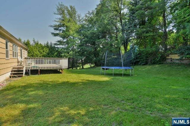 view of yard featuring a deck and a trampoline