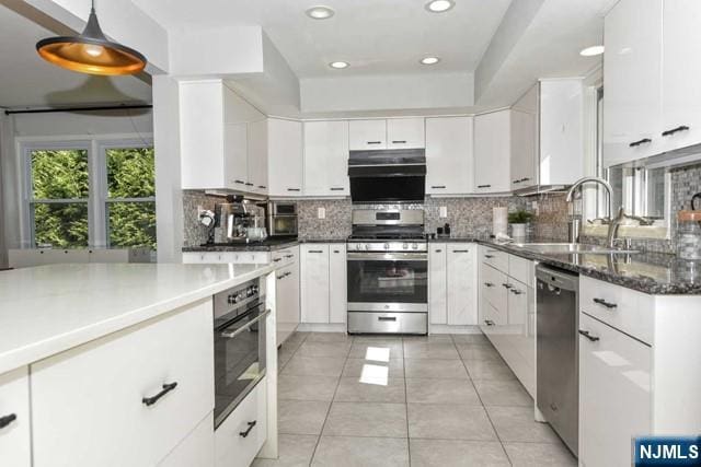kitchen featuring a sink, stainless steel appliances, white cabinetry, decorative backsplash, and light tile patterned floors