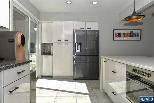 kitchen with light tile patterned floors, stainless steel fridge, recessed lighting, white cabinetry, and oven