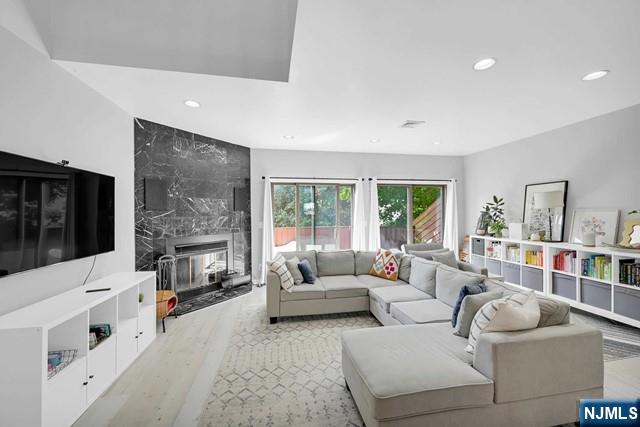 living area featuring a premium fireplace, light wood finished floors, and recessed lighting