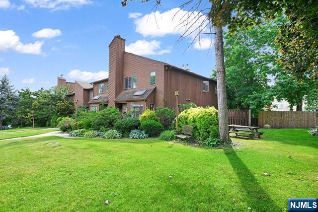 view of side of home with a chimney, a yard, and fence