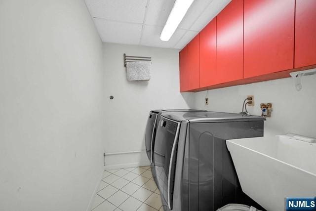 clothes washing area featuring light tile patterned floors, a sink, cabinet space, and washer and clothes dryer