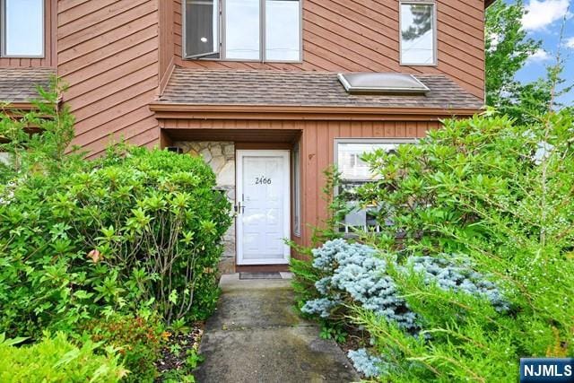 entrance to property with board and batten siding and roof with shingles