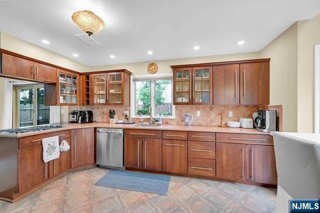 kitchen featuring stainless steel dishwasher, a sink, decorative backsplash, brown cabinets, and light countertops