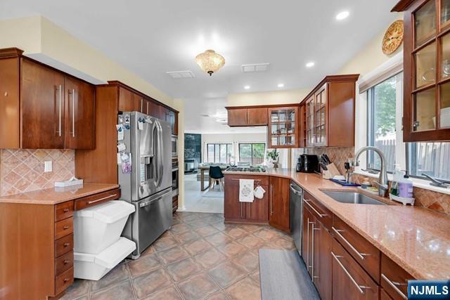 kitchen with a healthy amount of sunlight, stainless steel appliances, tasteful backsplash, and a sink