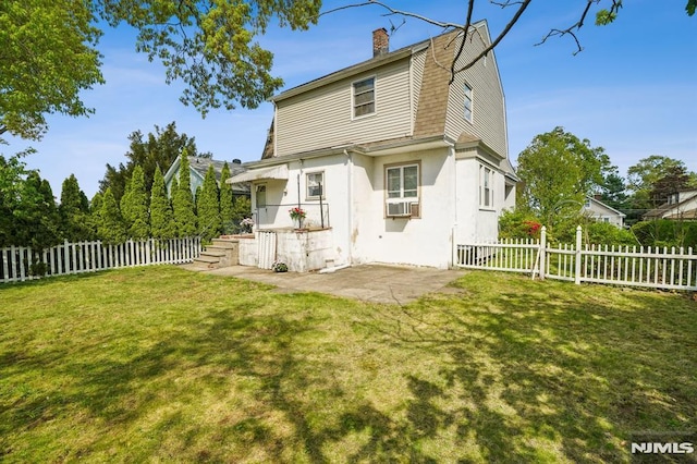 rear view of house with fence, a chimney, and a yard