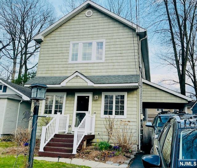 view of front of home with a shingled roof and a carport