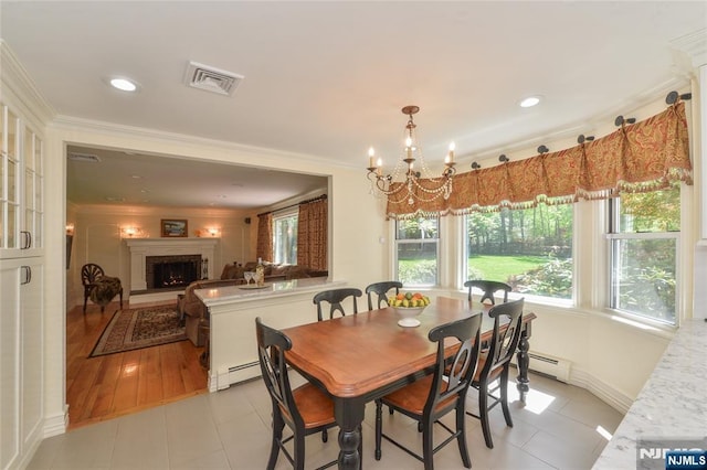 dining area with crown molding, a brick fireplace, a chandelier, baseboard heating, and light tile patterned flooring
