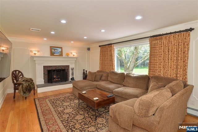 living room featuring a fireplace, ornamental molding, light wood-style flooring, recessed lighting, and baseboard heating