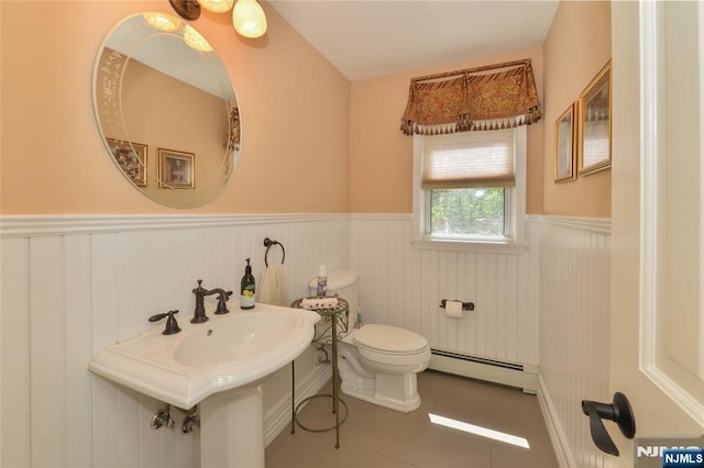 half bathroom with a baseboard radiator, a wainscoted wall, toilet, and tile patterned floors